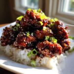 Close-up of Sticky Sweet Soy Chicken with Rice, coated in dark glaze and topped with sesame seeds and green onions.