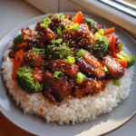 Close-up of a Sticky Teriyaki Chicken Bowl with Veggies served over white rice, garnished with sesame seeds and green onions.