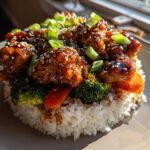 A perfectly molded Sticky Teriyaki Chicken Bowl with rice, broccoli, peppers, and sesame seeds.